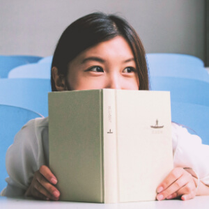 girl hiding behind a book